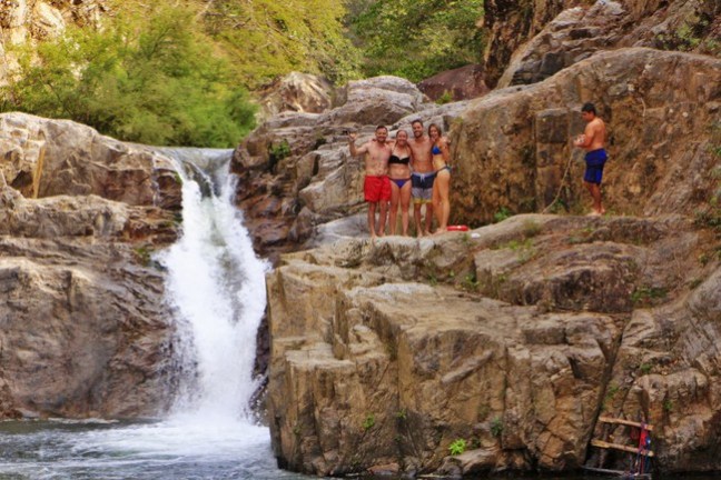 a group of people standing next to a waterfall