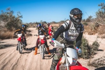 a man riding a motorcycle down a dirt road