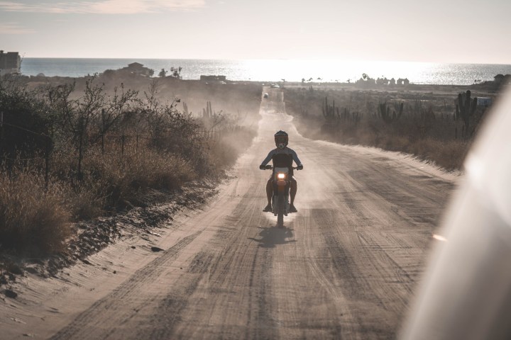 a man riding a motorcycle down a dirt road