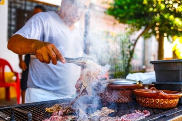 a person cutting a pizza on a grill